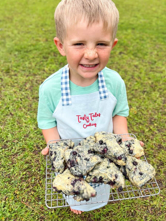 Child holding a tray of blueberry scones outdoors